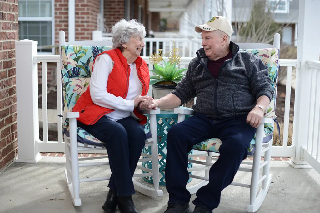 a man and woman smiling at each other while sitting on in rocking chairs