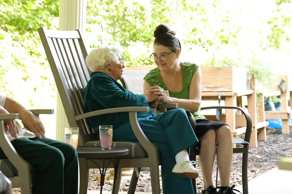 two women sitting on wooden chairs on a porch