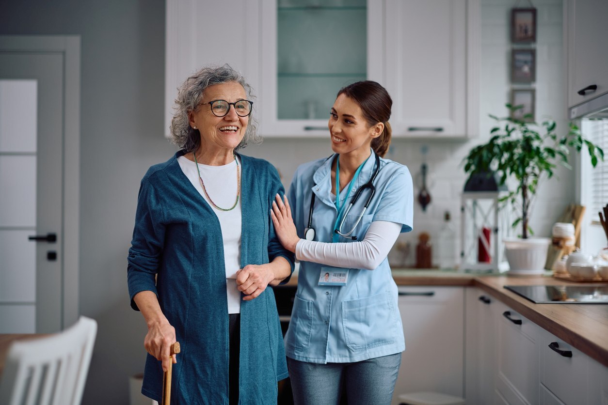 Woman with a cane being helped by an assisted living nurse.
